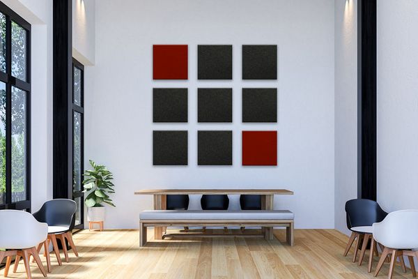 9 Rote und Anthrazitfarbene Akustikelemente in Form von Quadraten an einer hohen weißen Wand angebracht.