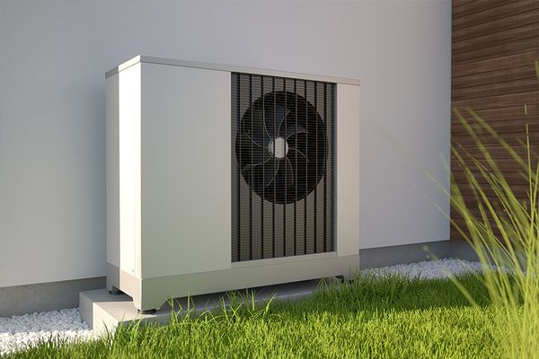 Moderne, weiße Wärmepumpe in einem Garten an einer Hauswand